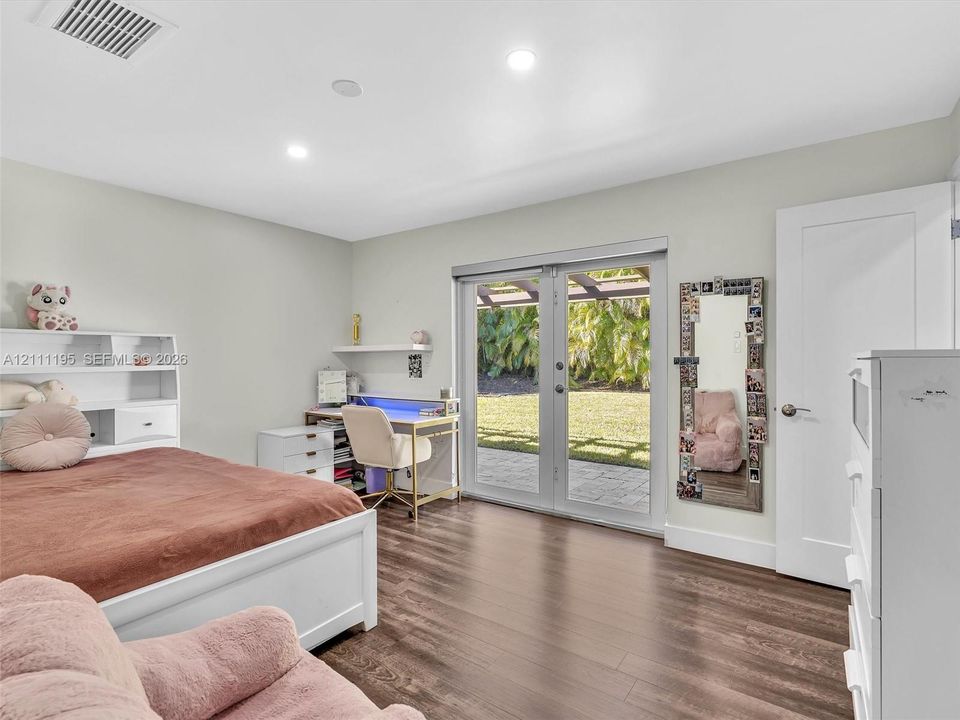 Wood-finish flooring, recessed lighting, and white built-in shelving, featuring glass French doors providing exterior access