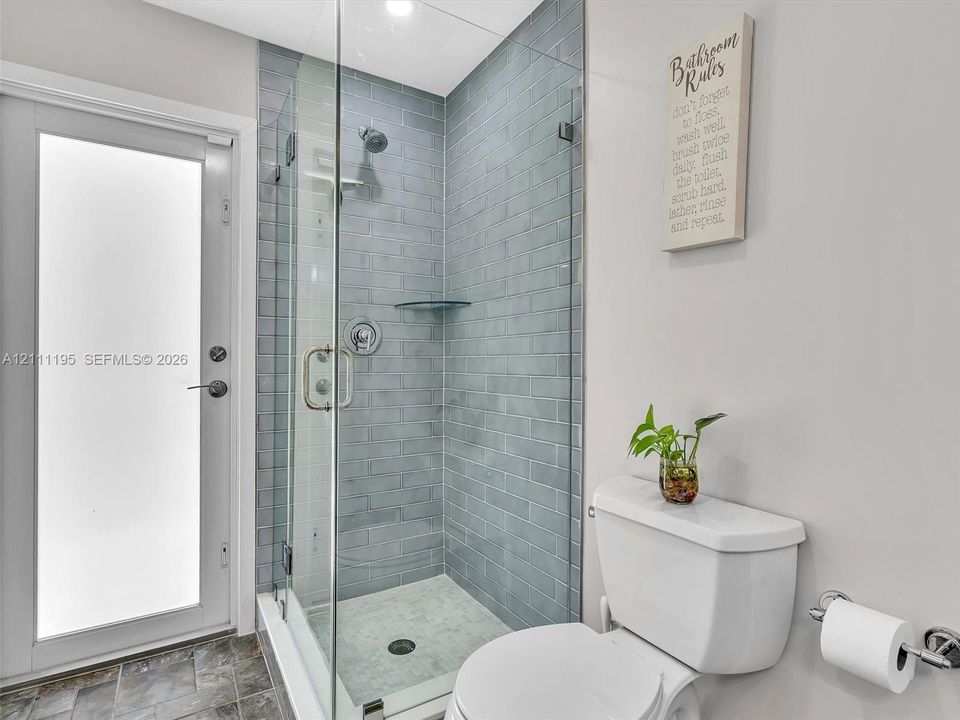 Walk-in shower featuring a glass enclosure, subway-style wall tile, built-in glass shelving, and a chrome shower fixture