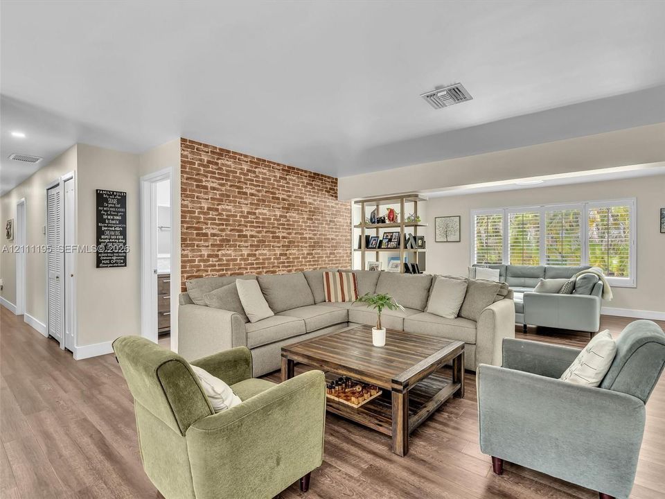 Exposed brick accent wall, wood-finish flooring, recessed lighting, and multi-pane windows with integrated shutters