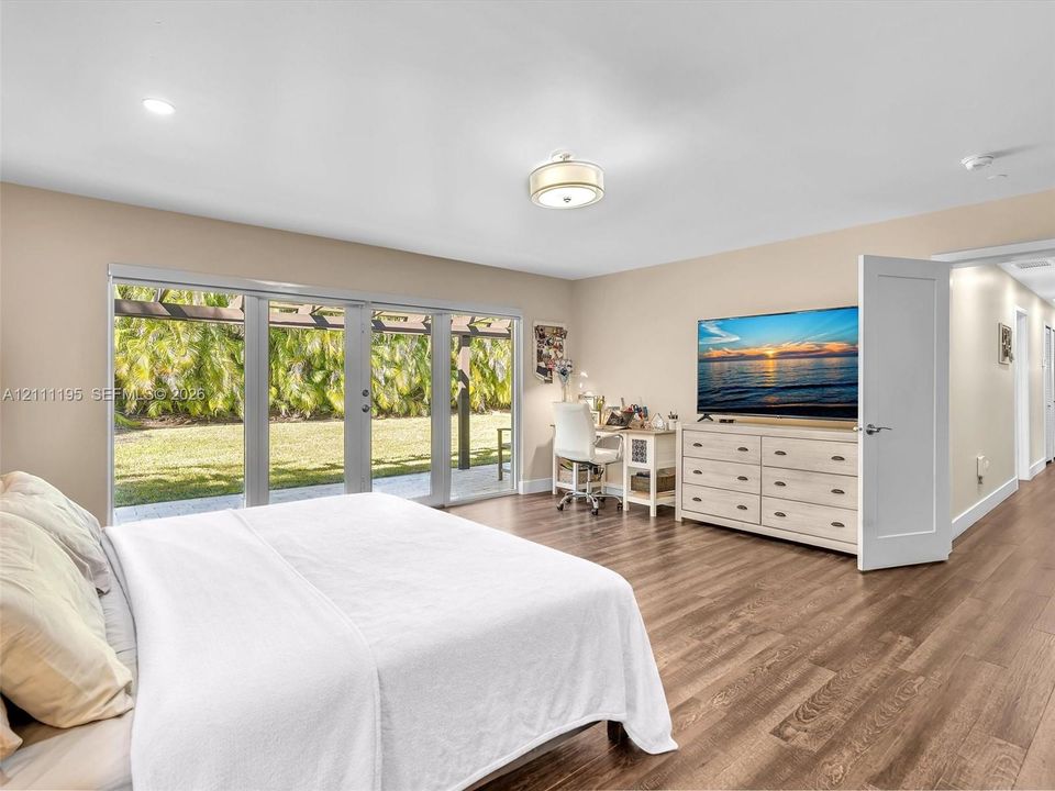 Wood-finish flooring, multi-panel glass sliding doors, recessed lighting, and a semi-flush mount ceiling fixture