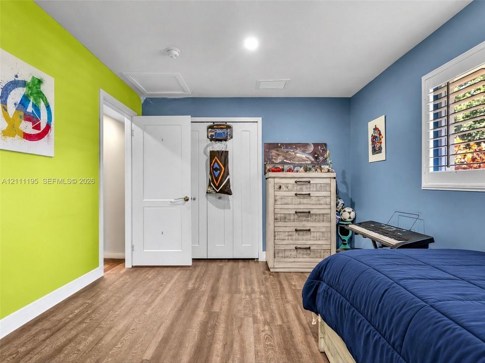 Room featuring wood-finish flooring, white panel doors, and window shutters