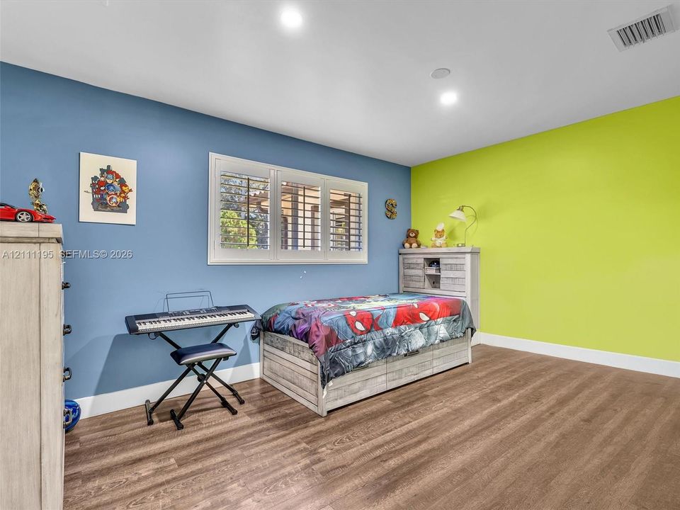 Room featuring wood-finish flooring, recessed lighting, and a multi-pane window with interior plantation shutters