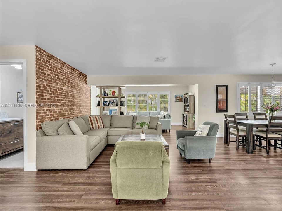 Exposed brick feature wall, wood-finish flooring, and window shutters
