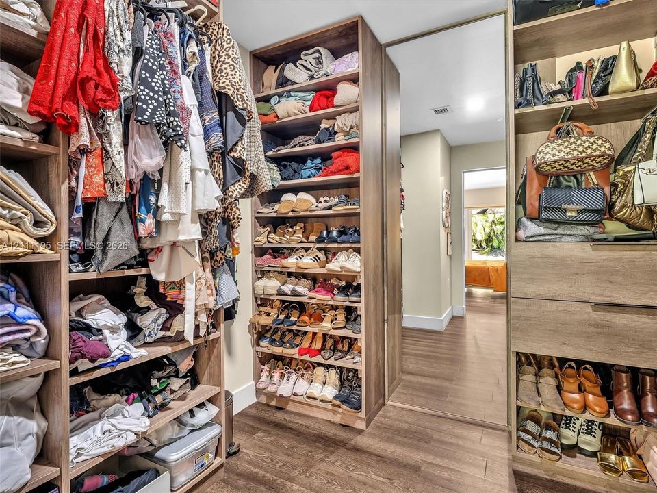 Custom wood-finish closet cabinetry with multiple tiers of shelving, integrated storage drawers, and floor-to-ceiling organization systems