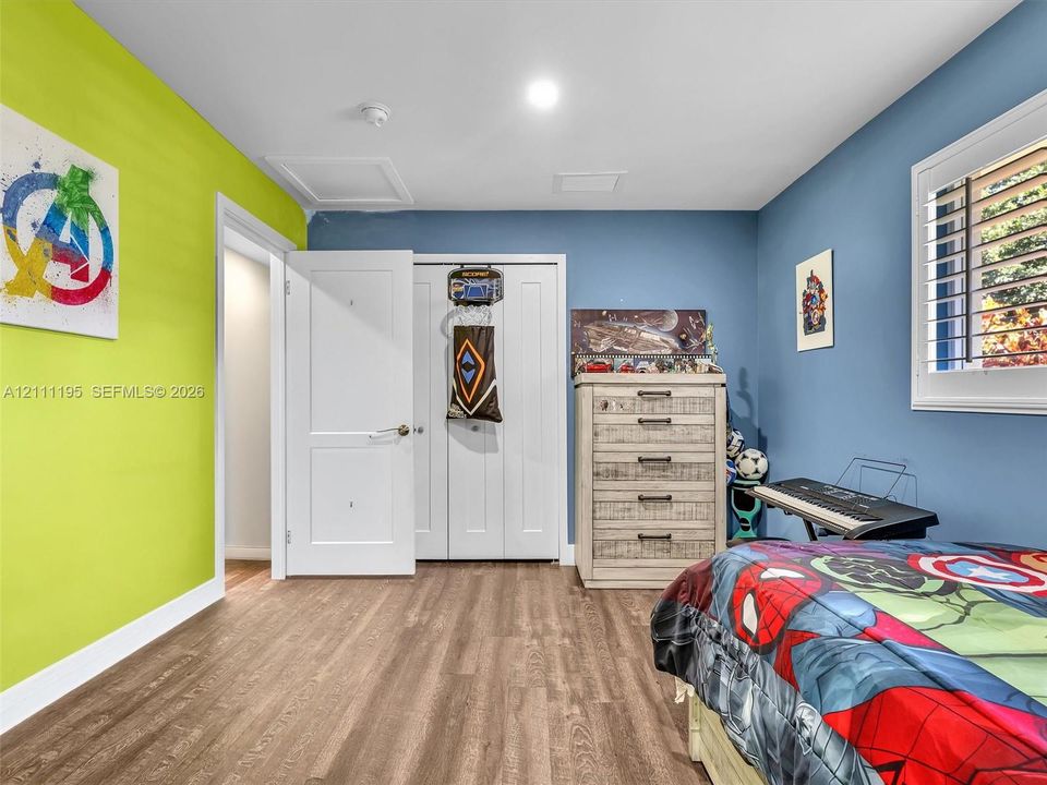 Wood-finish flooring, dual-panel interior door, white bi-fold closet doors, and window with adjustable shutters