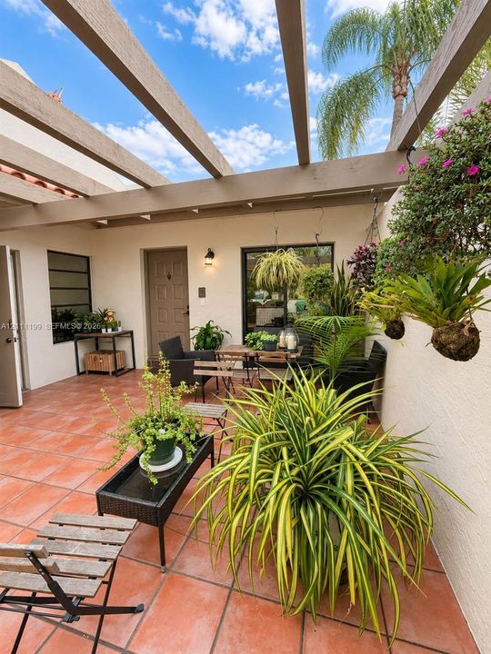 Private courtyard featuring terracotta tile flooring, a pergola, and stucco wall construction