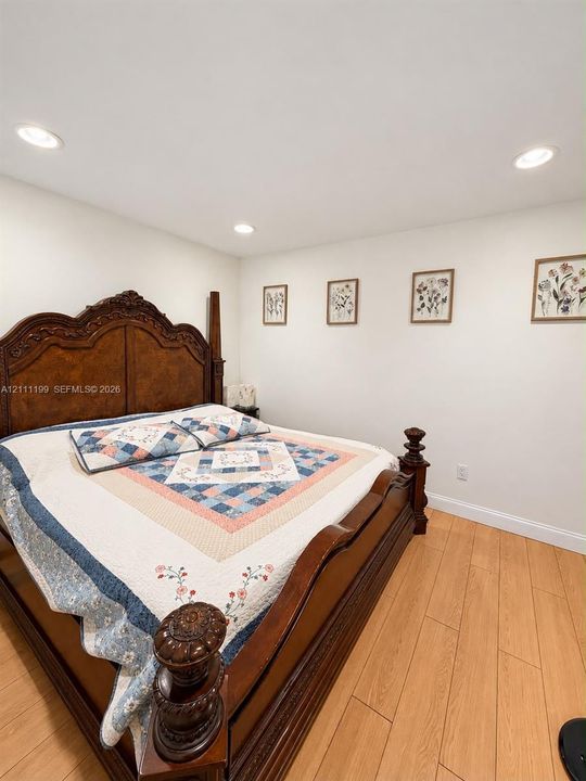 Neutral interior room featuring wood-finish flooring and recessed ceiling lighting