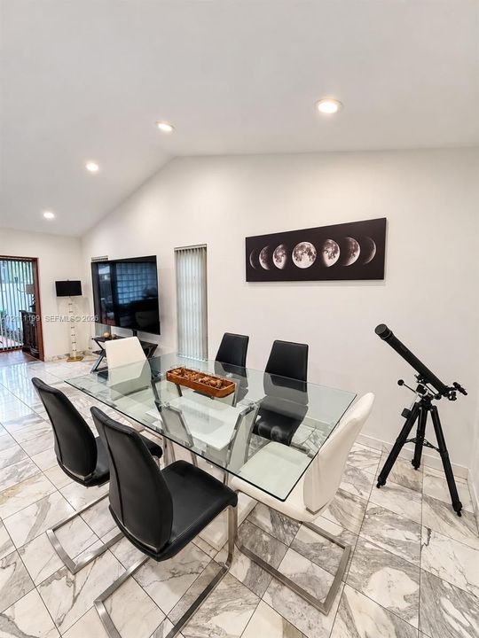 Vaulted ceilings with recessed lighting, complemented by large-format tile flooring and vertical blinds