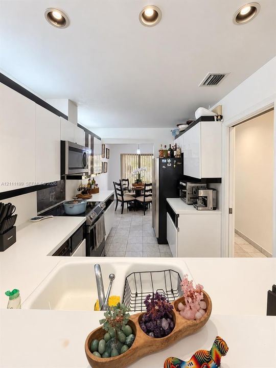 Kitchen featuring flat-panel high-gloss cabinetry, solid surface countertops, a dual-basin drop-in sink, recessed lighting, and tile flooring