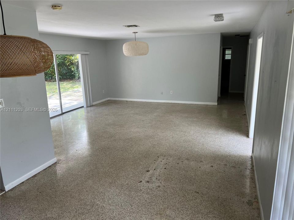 Open-concept interior featuring terrazzo flooring, sliding glass door, and dual woven pendant lighting fixtures