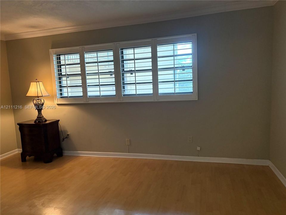 Expansive four-panel window featuring white plantation shutters and wood-finish flooring