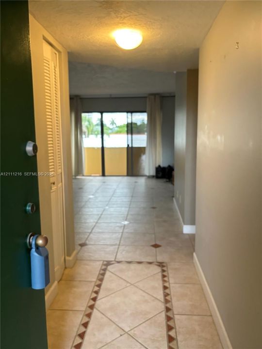 Entryway featuring neutral tile flooring with a decorative geometric border, louvered bi-fold closet doors, and flush-mount ceiling lighting
