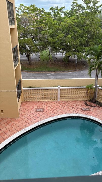 Outdoor swimming pool featuring a tiled deck area and a decorative concrete block privacy wall