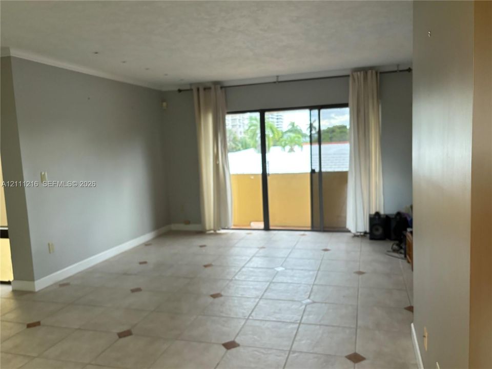 Open living area featuring neutral tile flooring with inlay accents, recessed ceiling lighting, and sliding glass doors providing outdoor access