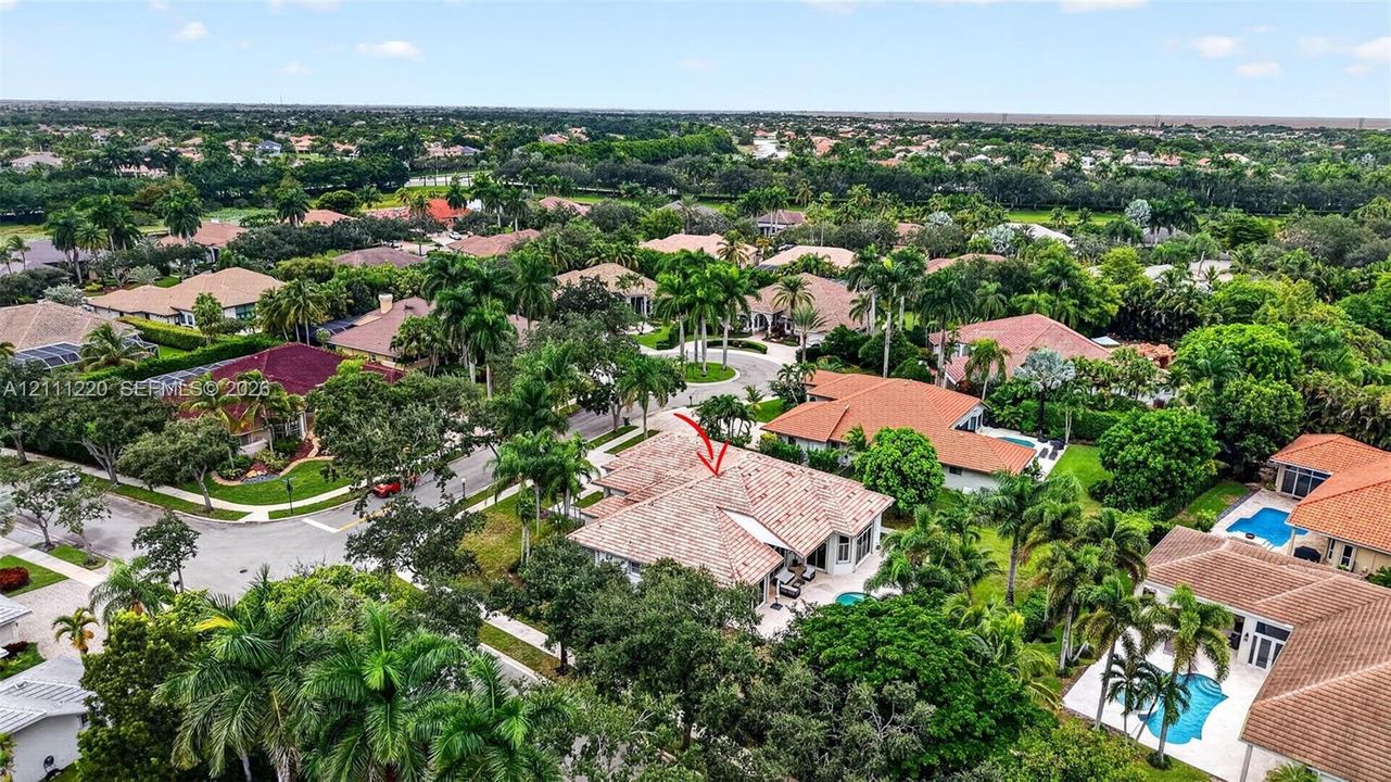 Aerial perspective of a residential property featuring a tiled roof, multi-car garage, and mature landscaping in a suburban setting