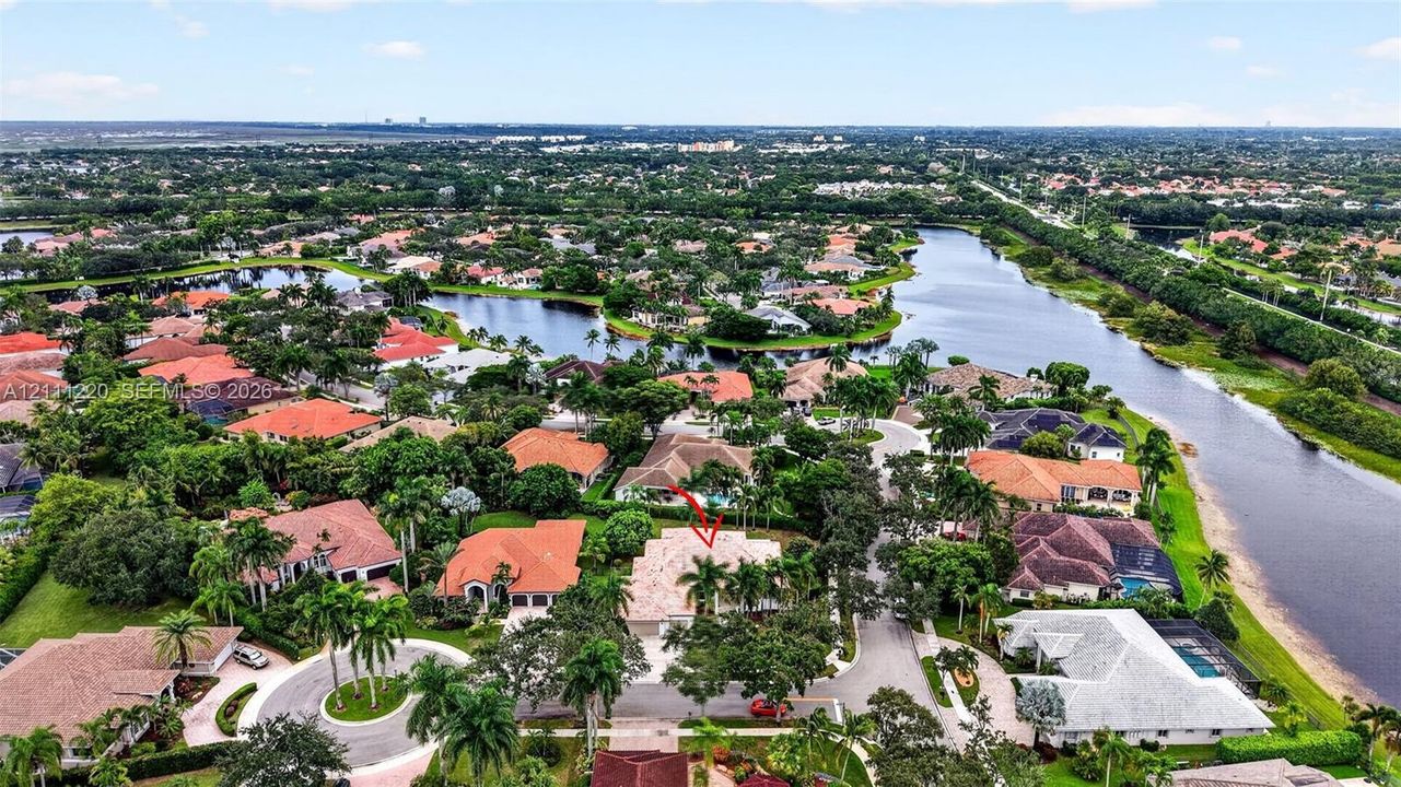 Aerial perspective of a residential property situated in a planned community featuring tile roofing, mature landscaping, and proximity to regional waterways