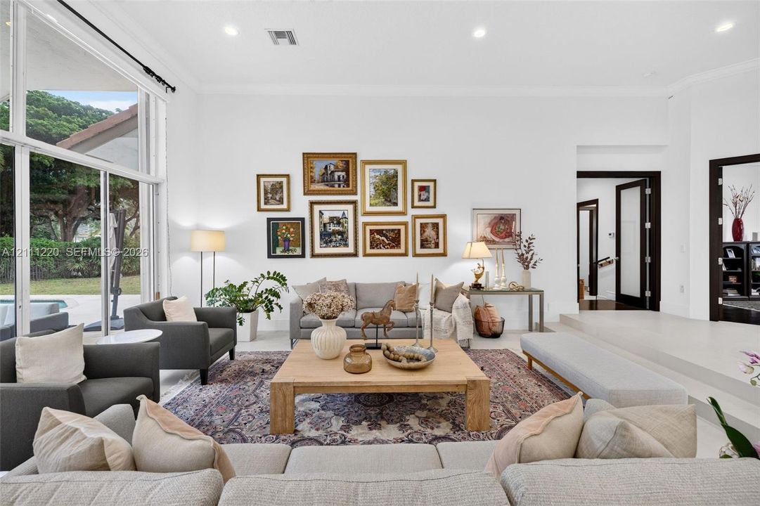 Living area featuring high ceilings, large-format tile flooring, recessed lighting, and expansive floor-to-ceiling windows