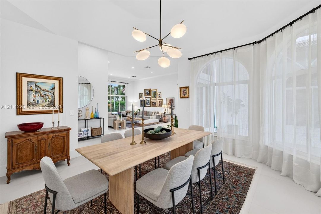 Dining space featuring arched windows, light-toned flooring, and a multi-arm modern chandelier