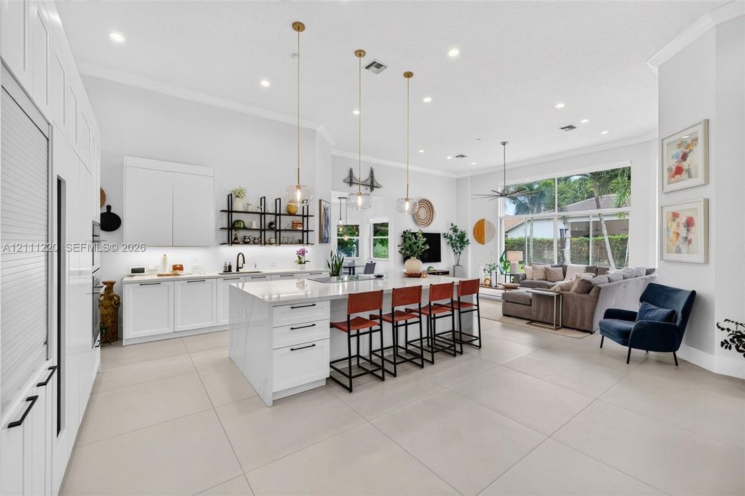 Kitchen featuring a large central island with quartz surfacing, floor-to-ceiling white cabinetry, matte black hardware, recessed lighting, and large-format tile flooring