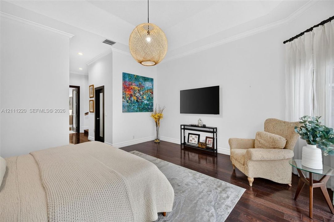 Tray ceiling, dark wood-finish flooring, crown molding, and woven spherical pendant lighting