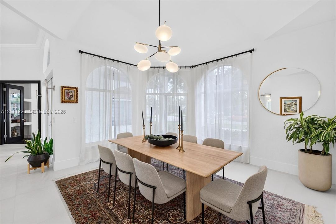 Dining area featuring three large arched windows, vaulted ceiling, and a modern multi-globe chandelier with a metal finish