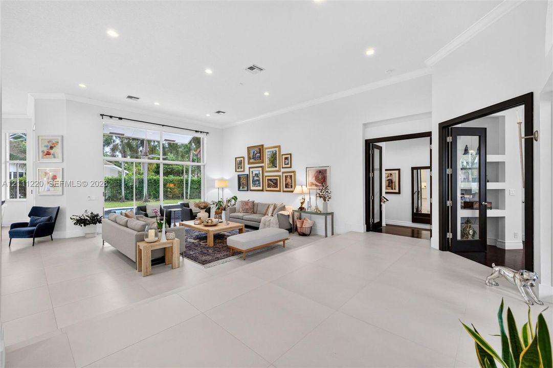 Spacious interior featuring large-format tile flooring, recessed lighting, expansive floor-to-ceiling windows, and French doors with dark-finished trim