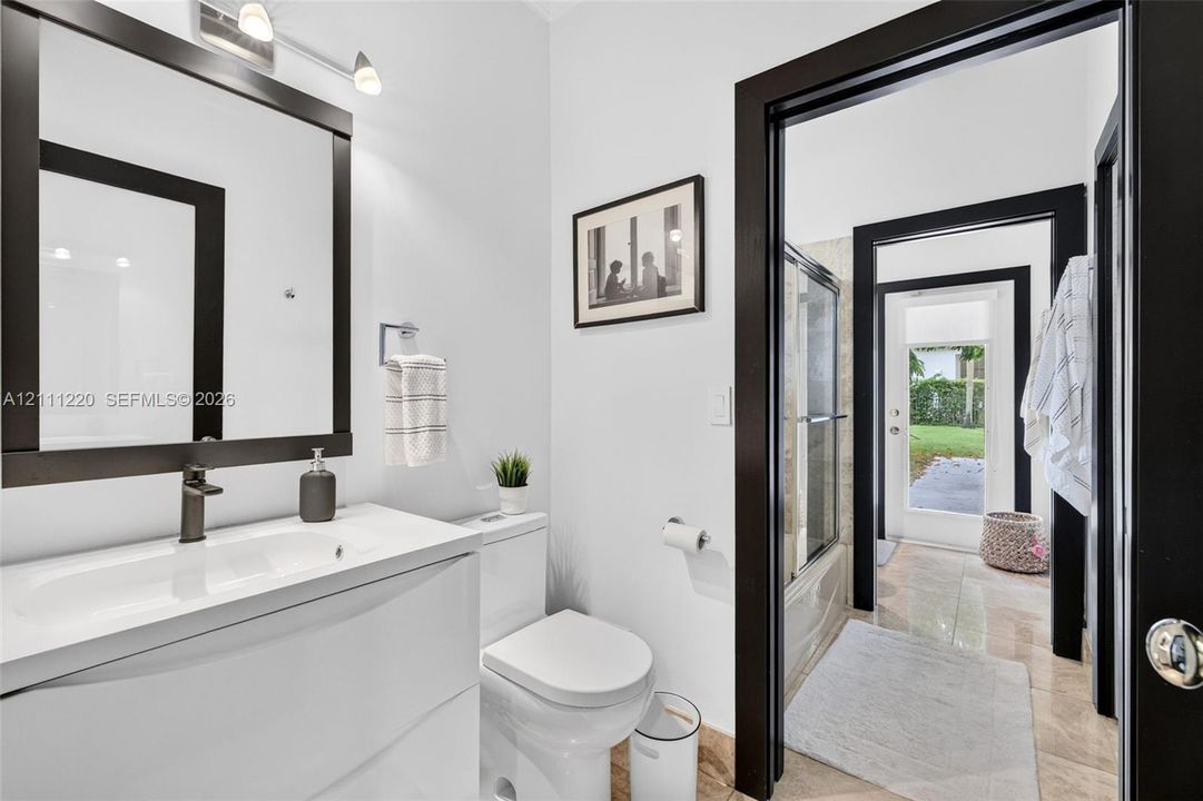 Bathroom featuring a white vanity with an integrated sink, dark-finish faucet, framed wall-mounted mirror, and black door casings