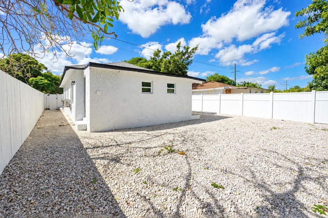 Sunny Gravel Yard and White Fenced House
