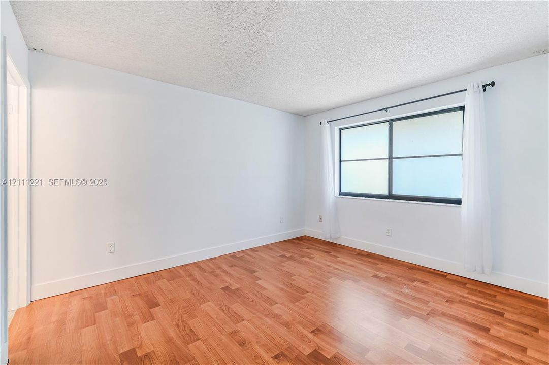 Interior room featuring wood-finish flooring, a large horizontal slider window, and neutral wall paint