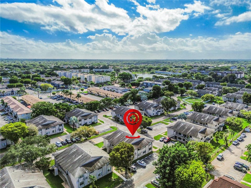 Aerial perspective of multi-family residential structures featuring pitched roofing and integrated surface parking