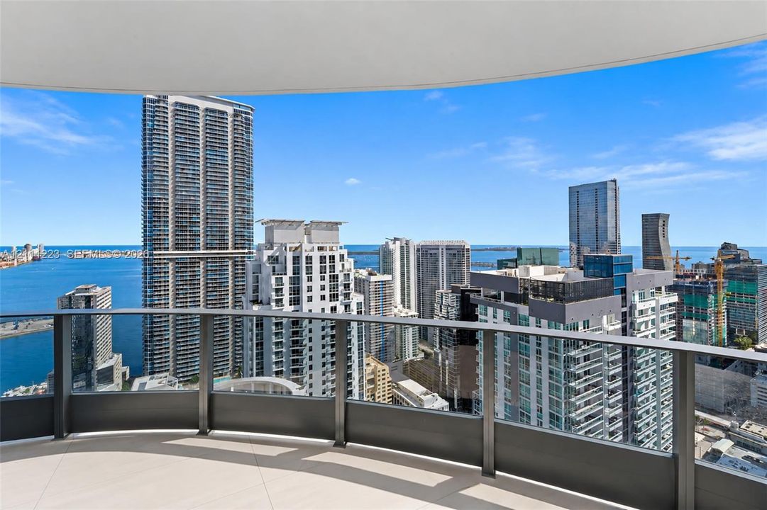 Curved covered balcony featuring large-format tile flooring and dark metal railing