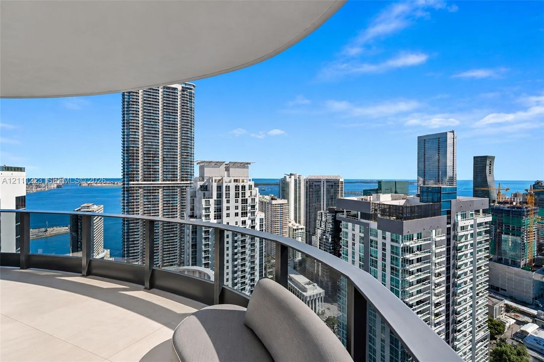 Curved balcony featuring light-colored tile flooring and a glass-paneled railing