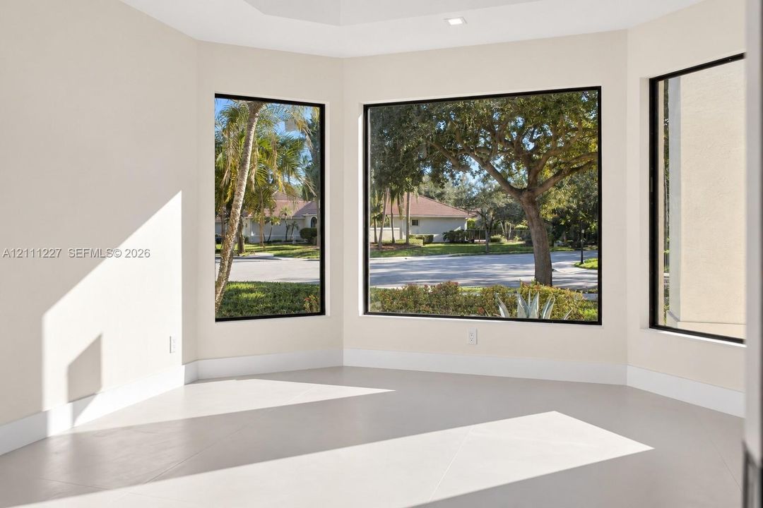 Expansive room featuring a multi-panel window bay, neutral wall finishes, recessed ceiling lighting, and large-format tile flooring