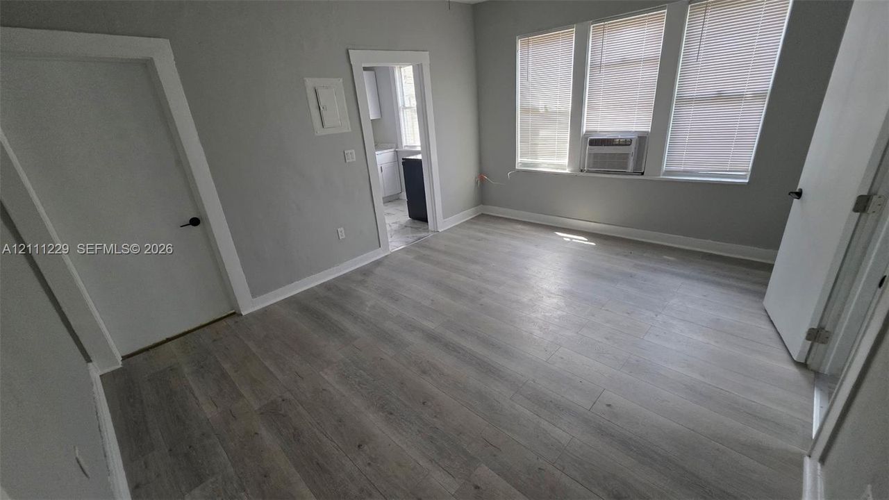 Neutral-toned interior featuring wood-finish flooring, multi-pane windows, and high-contrast door casings
