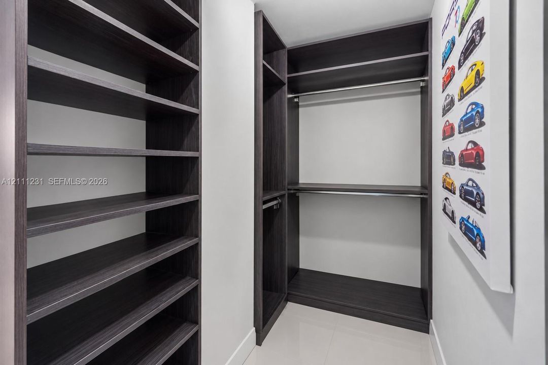 Custom walk-in closet featuring dark wood-finish shelving, integrated hanging rods, and multiple open storage compartments