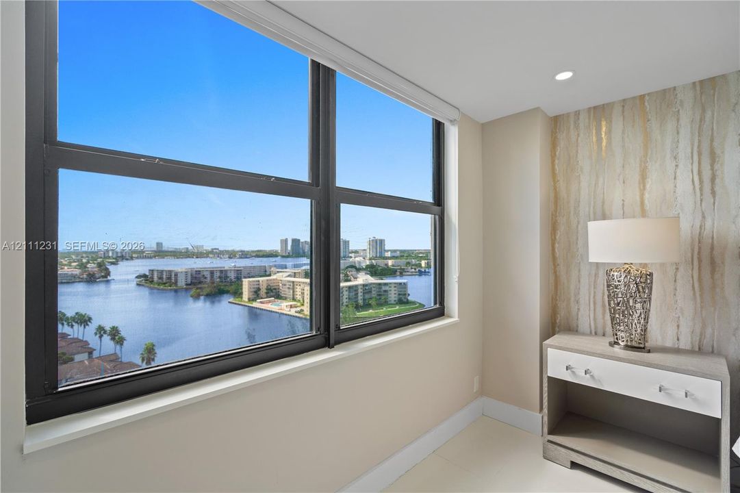 Large-format window featuring black framing, expansive water scenery, and neutral wall tones with stone-textured accent wall