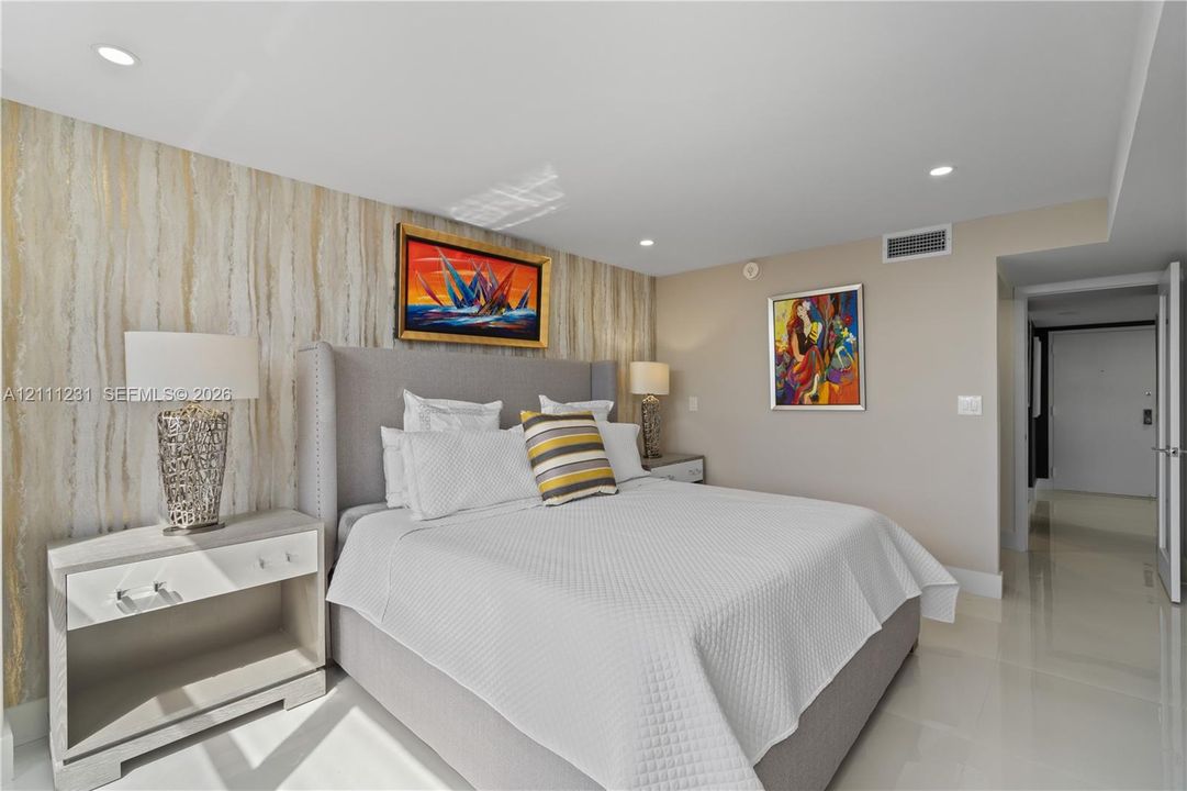 Textured accent wall with vertical stone-pattern surfacing, recessed ceiling lighting, and polished stone-finish flooring