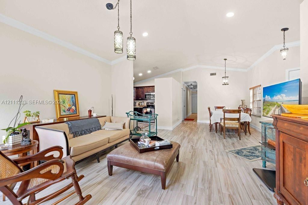 Open-concept interior featuring wood-finish flooring, recessed lighting, crown molding, and decorative pendant fixtures