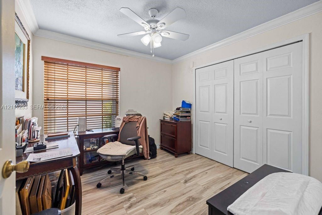 Room featuring wood-finish flooring, crown molding, a ceiling fan with integrated lighting, dual-pane horizontal blinds, and a dual-panel sliding closet