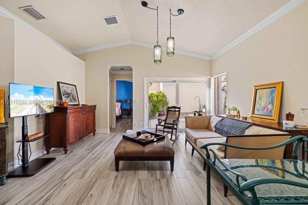 Vaulted ceilings featuring decorative pendant lighting, sliding glass doors, and wood-finish flooring