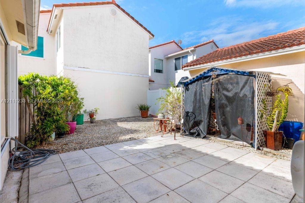 Private courtyard featuring square paver patio, stone-surfaced ground, and stucco exterior walls