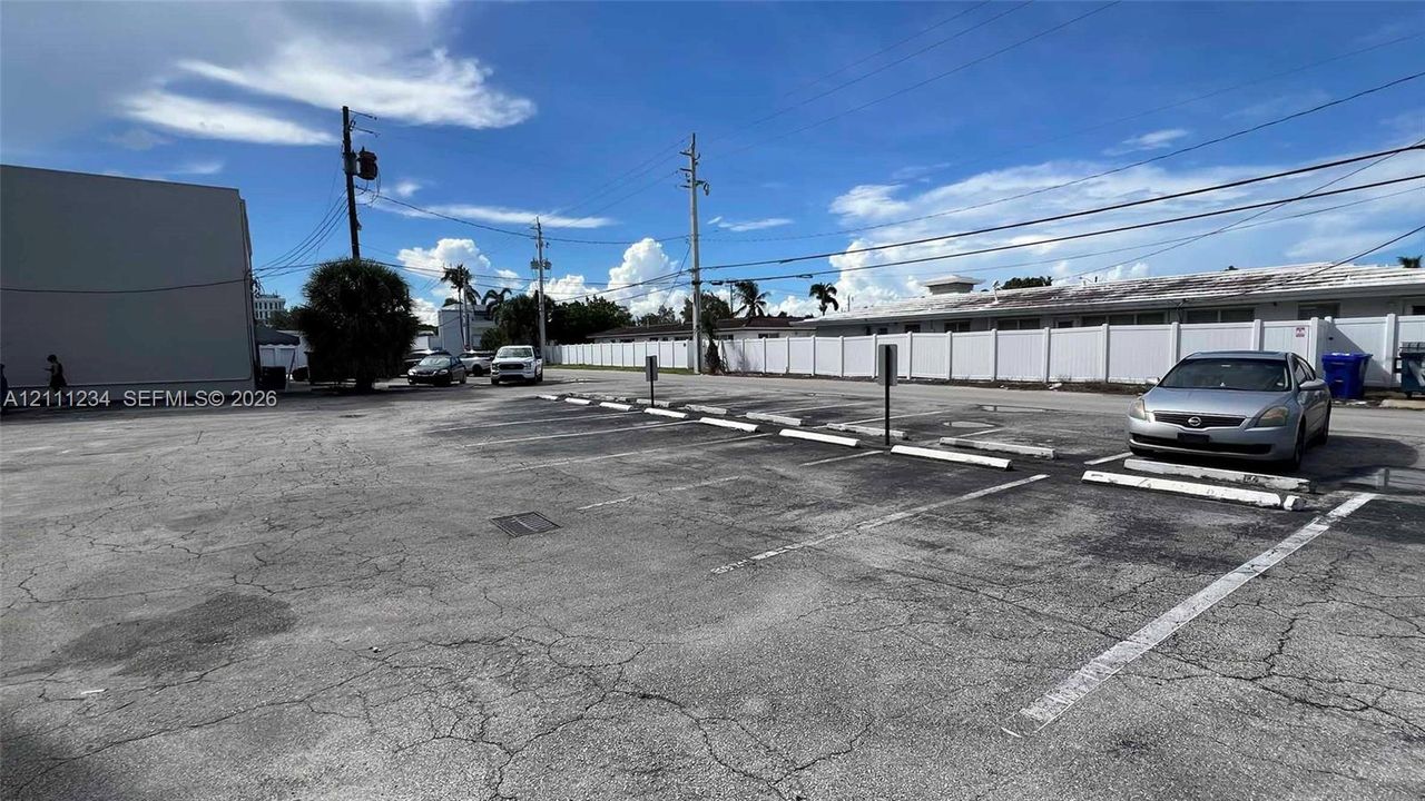 Paved off-street parking area featuring marked spaces and concrete wheel stops