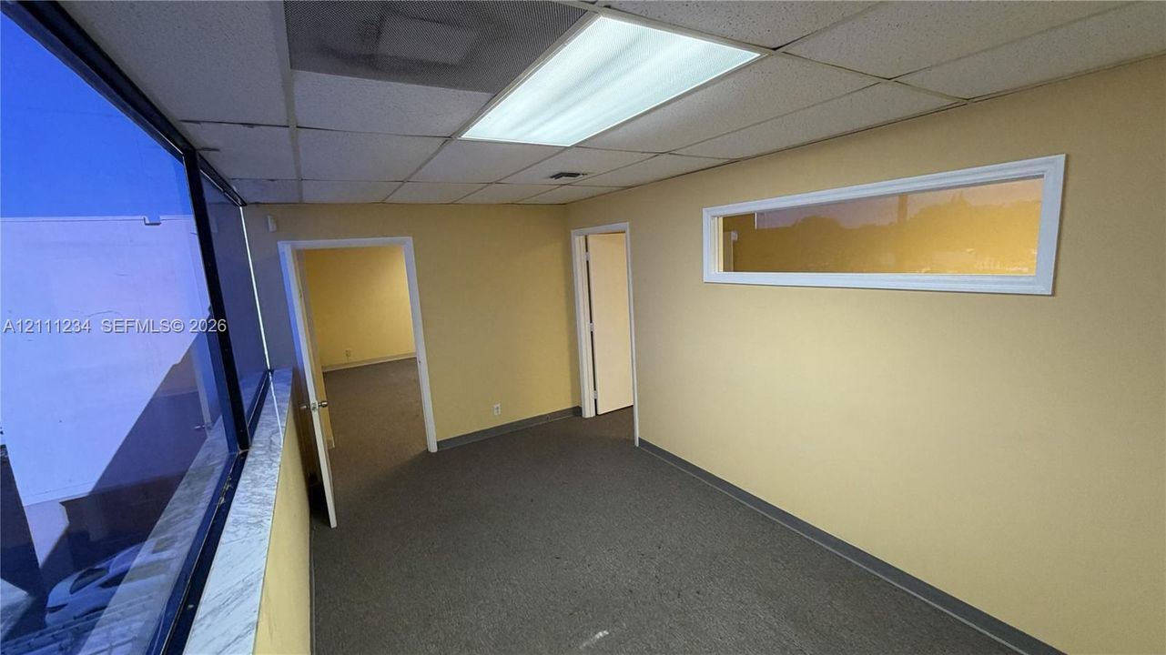 Interior space featuring expansive glass paneling, horizontal transom window, neutral-toned wall finish, drop ceiling with recessed lighting, and carpeting