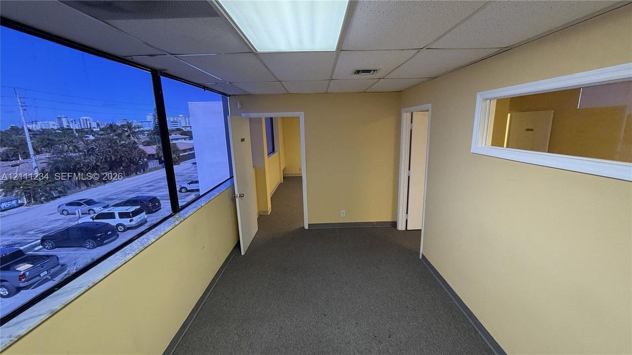 Interior space featuring expansive floor-to-ceiling windows, recessed lighting, neutral carpet flooring, and a horizontal interior transom window