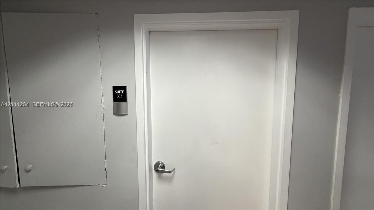Solid core door featuring a stainless steel lever handle and a mounted suite identification plaque