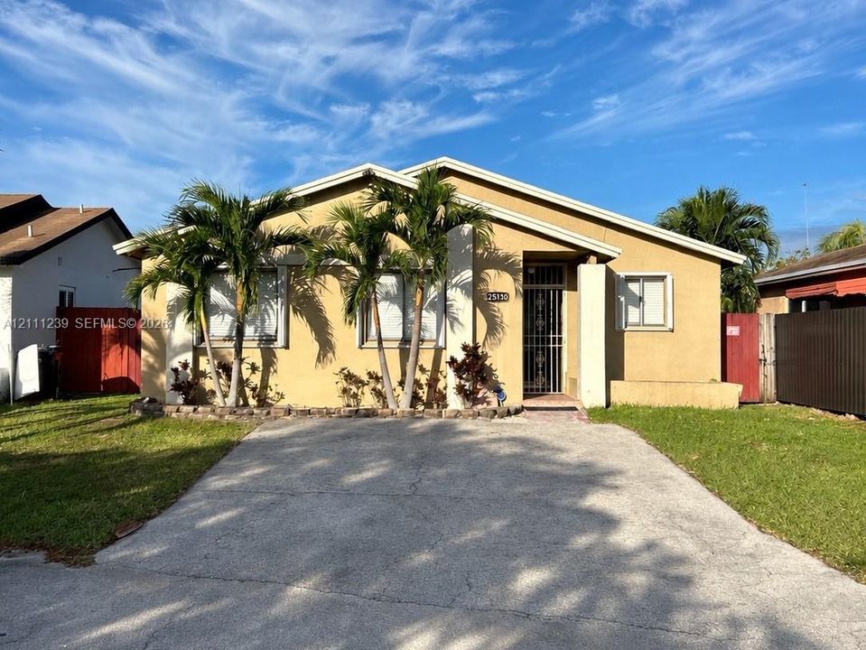 Single-story residence featuring a stucco exterior, concrete driveway, front landscape planting beds, and a metal security door