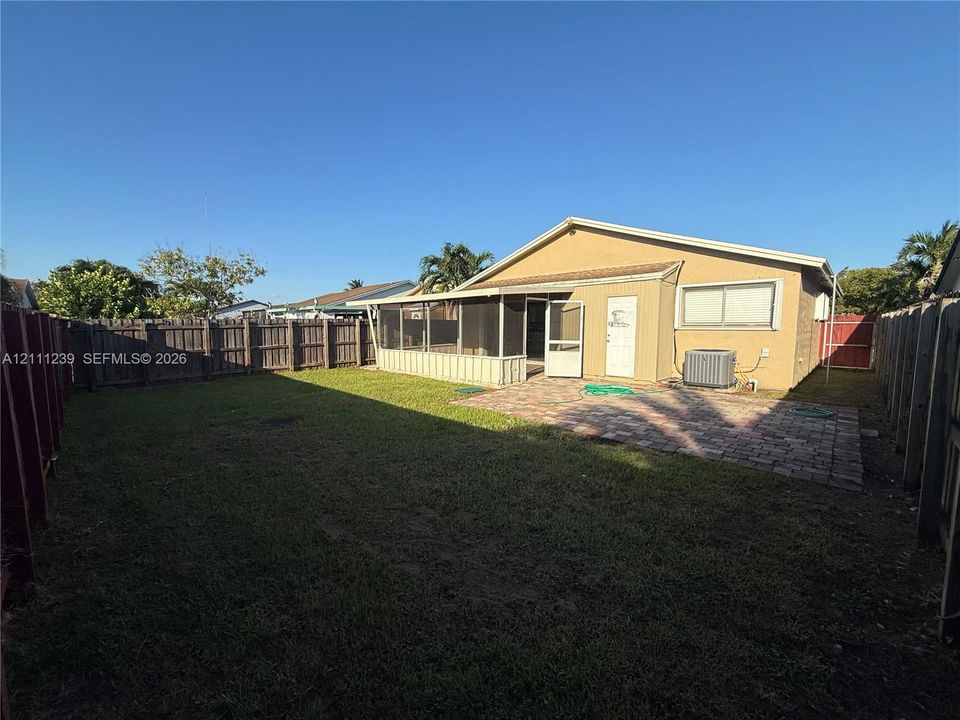 Backyard featuring a screened-in lanai, paver patio, and full perimeter wood fencing