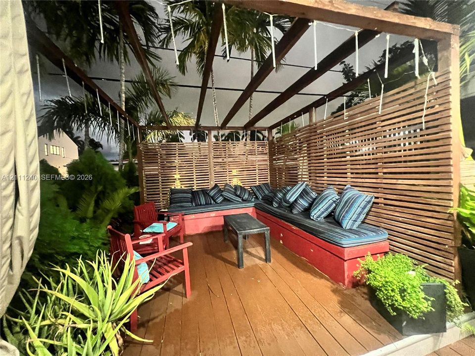 Outdoor deck featuring a wood-slat privacy screen, an overhead timber pergola, and built-in masonry seating