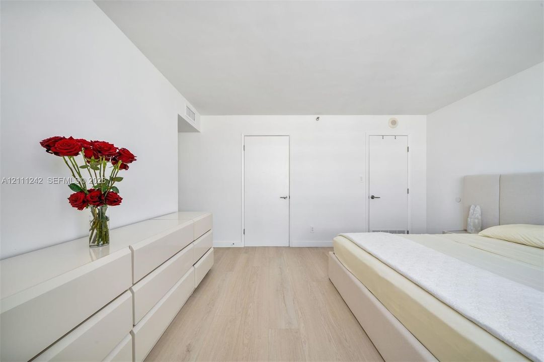 Neutral-toned space featuring light-finish flooring, crisp white walls, and two solid-core interior doors
