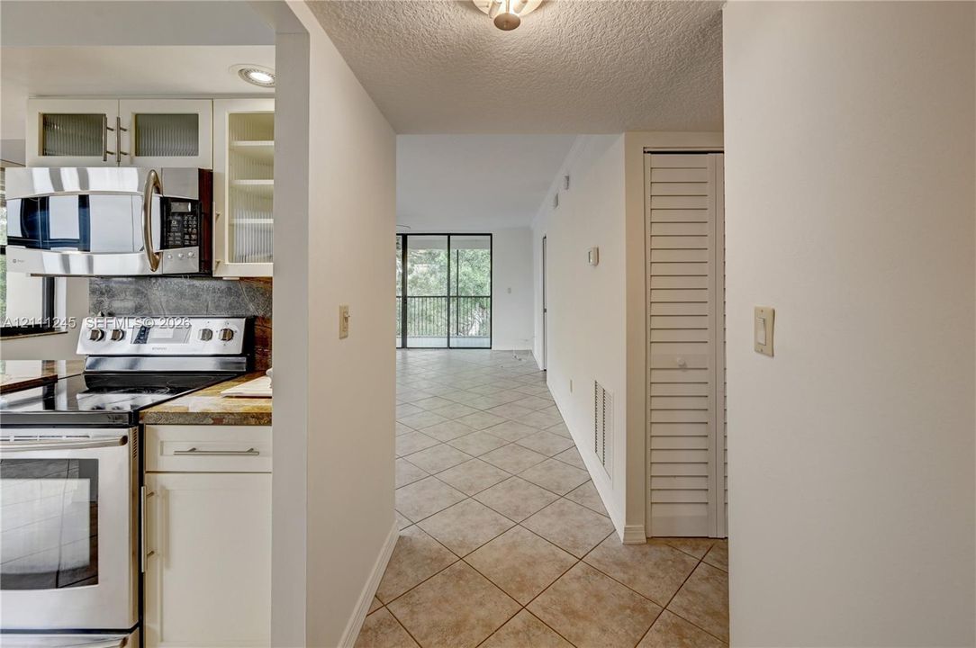 Kitchen featuring stainless steel appliances, white cabinetry, stone-finish countertops, and tile flooring